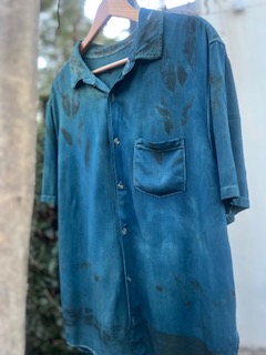 A blue indigo botanical printed shirt hanging on a wooden hanger
