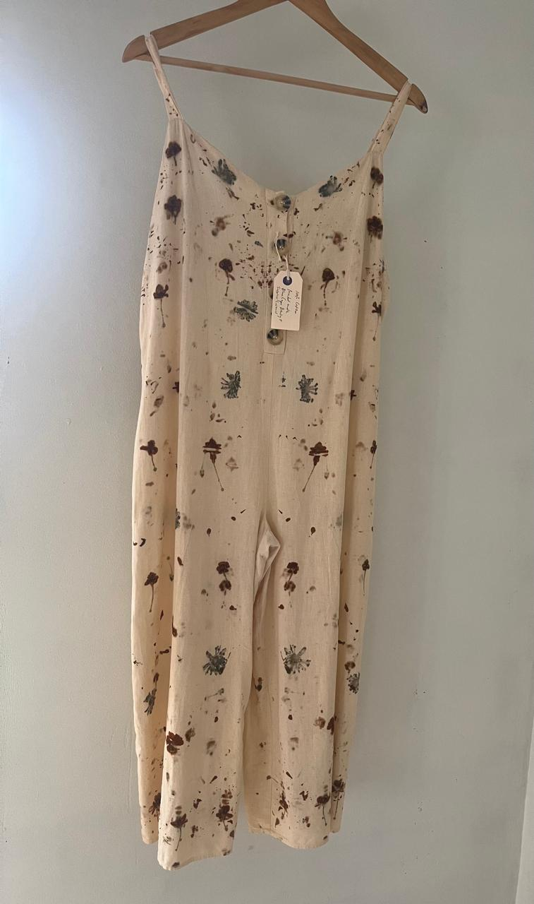 A botanical printed cotton dress with eucalyptus and rust leaf marks hanging on a wooden hanger