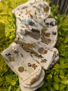Eco-printed botanical socks folded among fresh green leaves