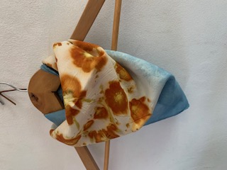 A marigold and indigo printed cloth draped over a wooden drying stand