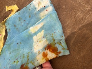 An indigo and rust botanical printed cloth held in the hand