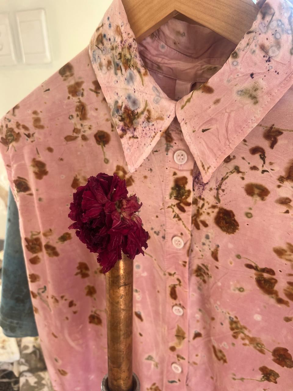 A soft pink botanical printed shirt with a dried burgundy flower