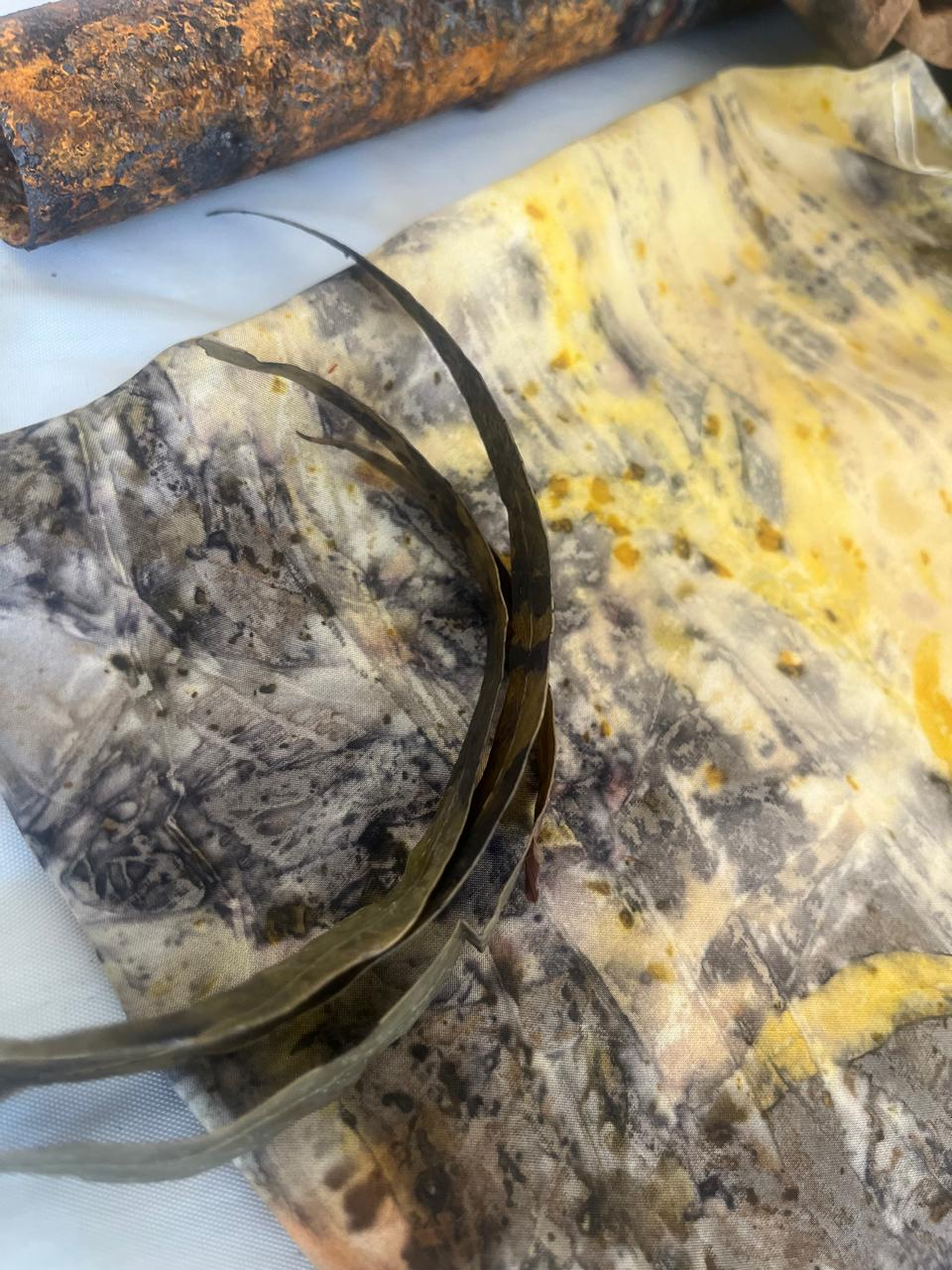 A rust-printed textile with eucalyptus leaves and subtle yellow botanical marks