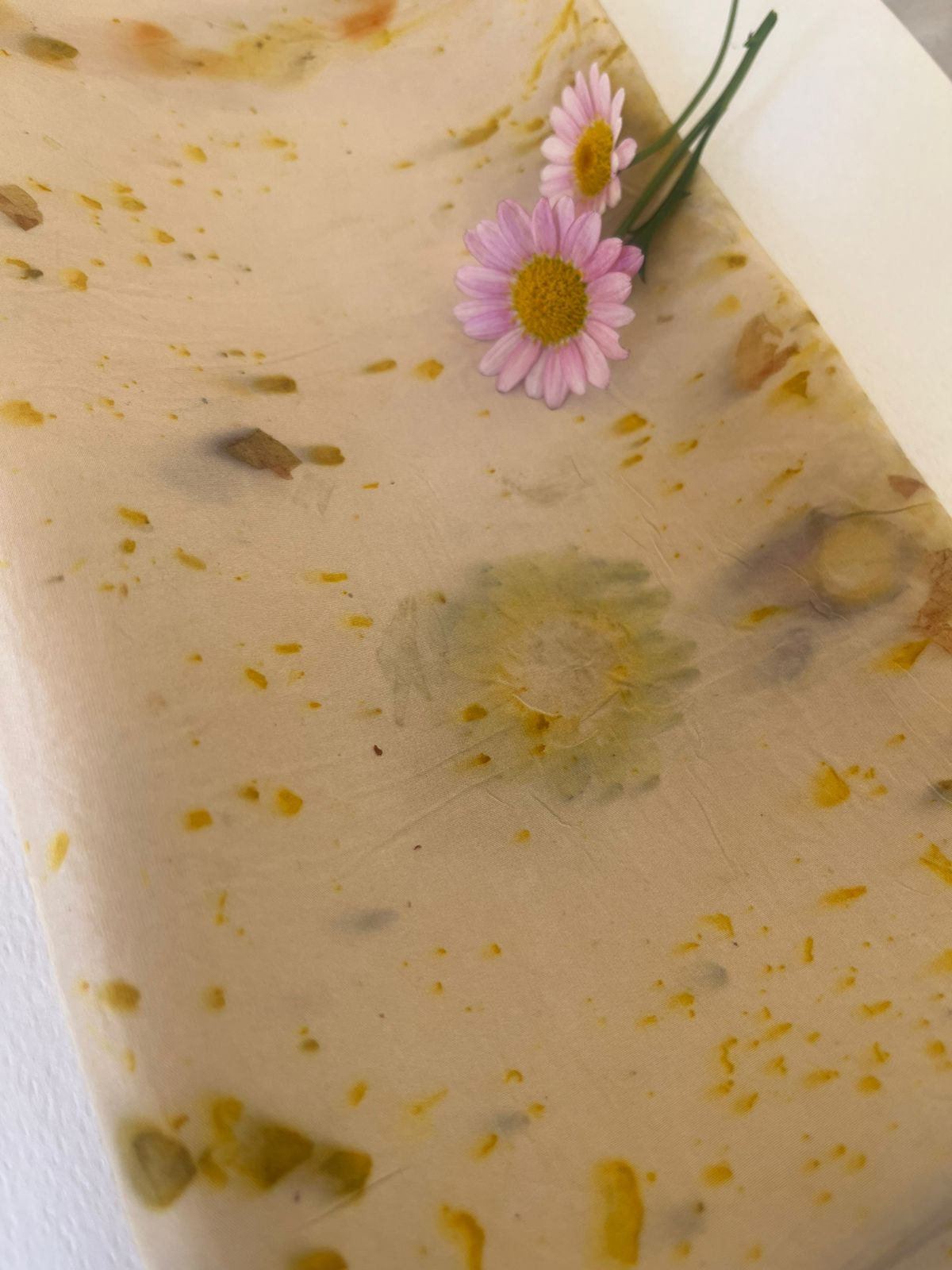 A delicate botanical printed scarf with pink daisies and soft yellow marks