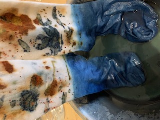 Botanical-printed socks being dipped into a living indigo vat