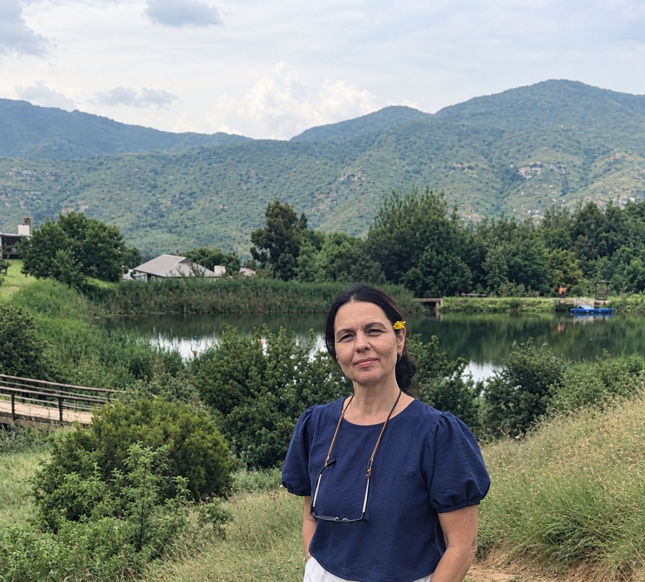 Marinda by a lake with mountains and wildflowers in her hair