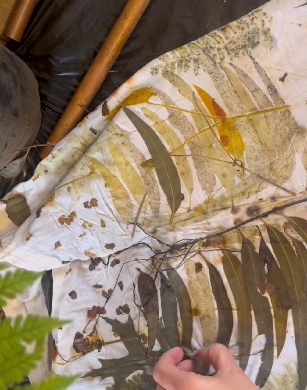 Eucalyptus and autumn leaves arranged on white cotton before bundling