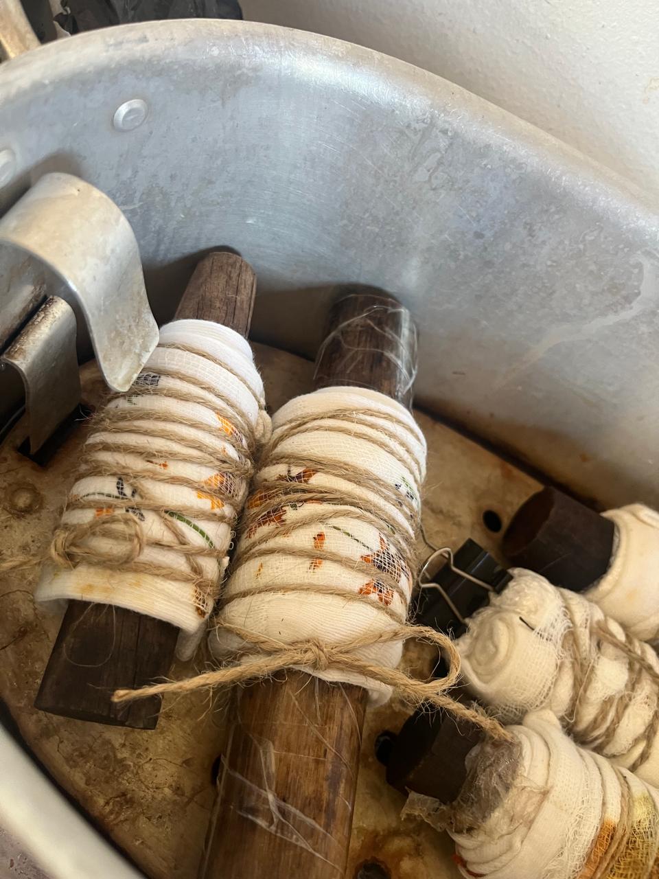 Wrapped botanical bundles resting inside the large metal steaming pot