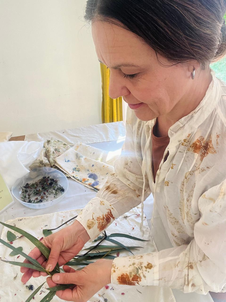 Marinda arranging fresh leaves onto cloth at the KAIA studio table