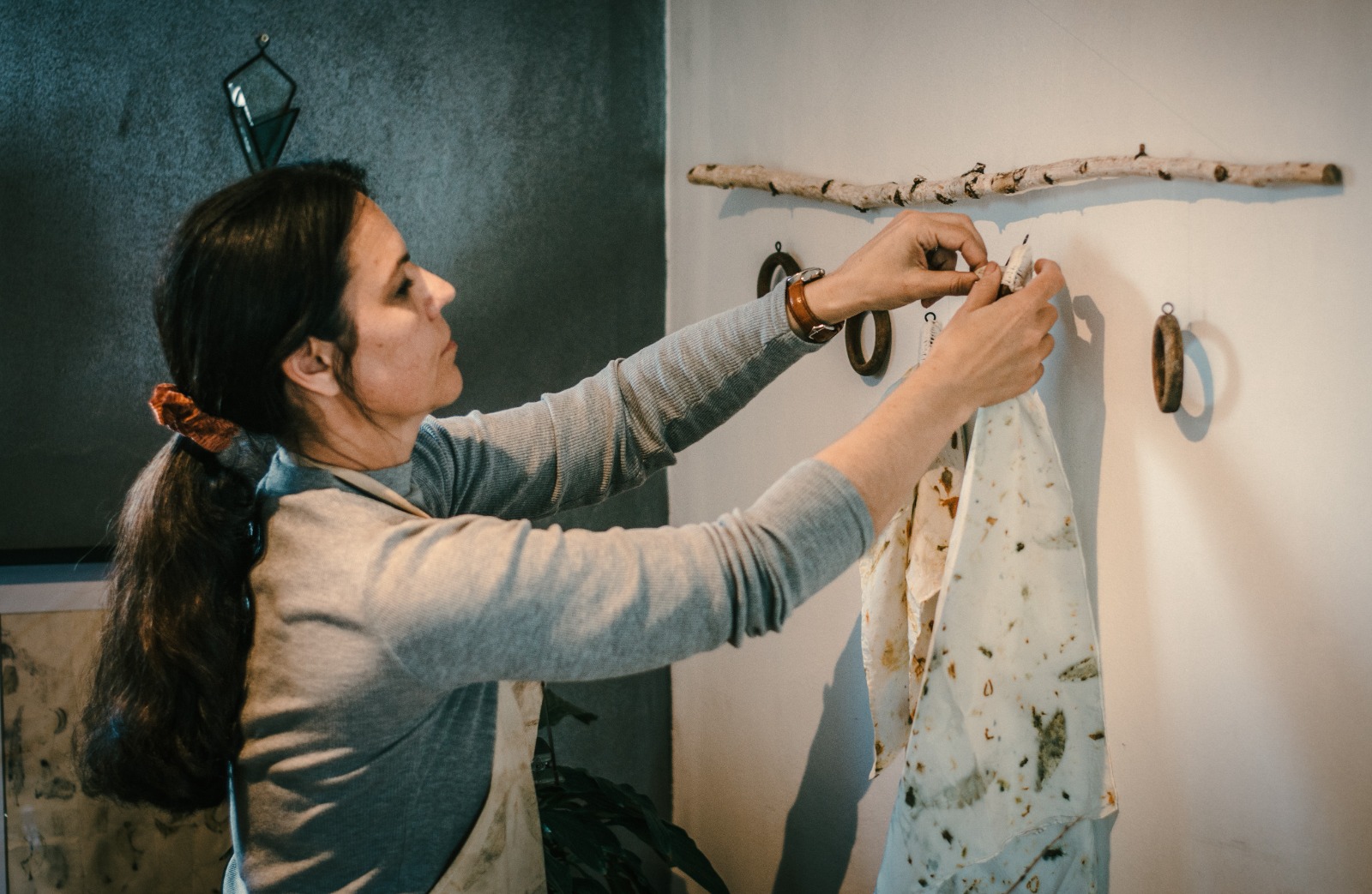 Marinda hanging a freshly printed botanical cloth on a branch rail in the studio
