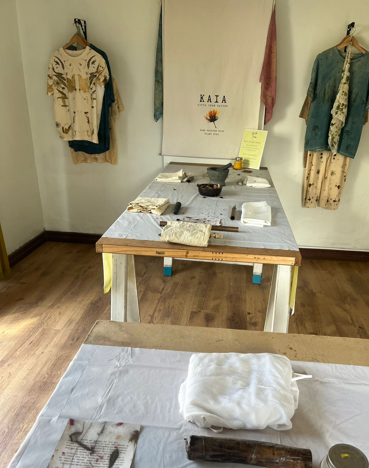 Botanical printed garments and the KAIA banner arranged in the studio