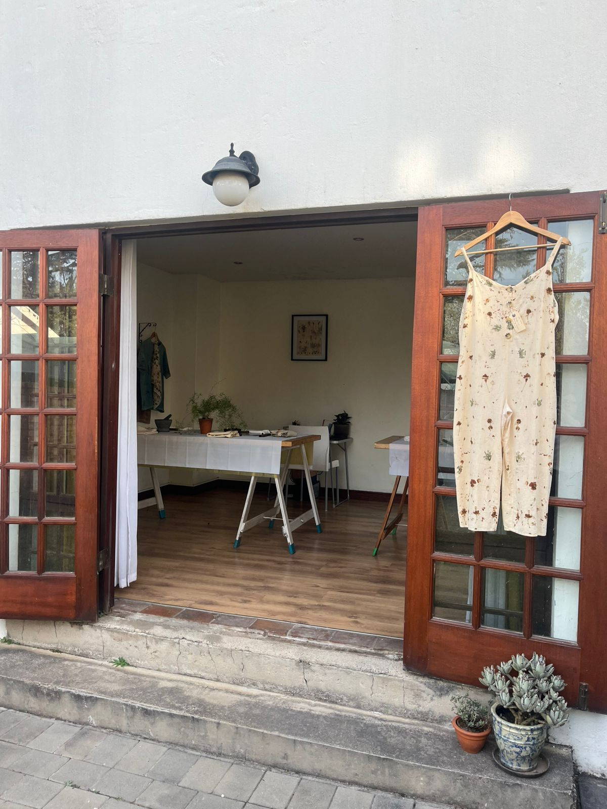 A botanical printed dress hanging on the wooden studio door in Glen Marais