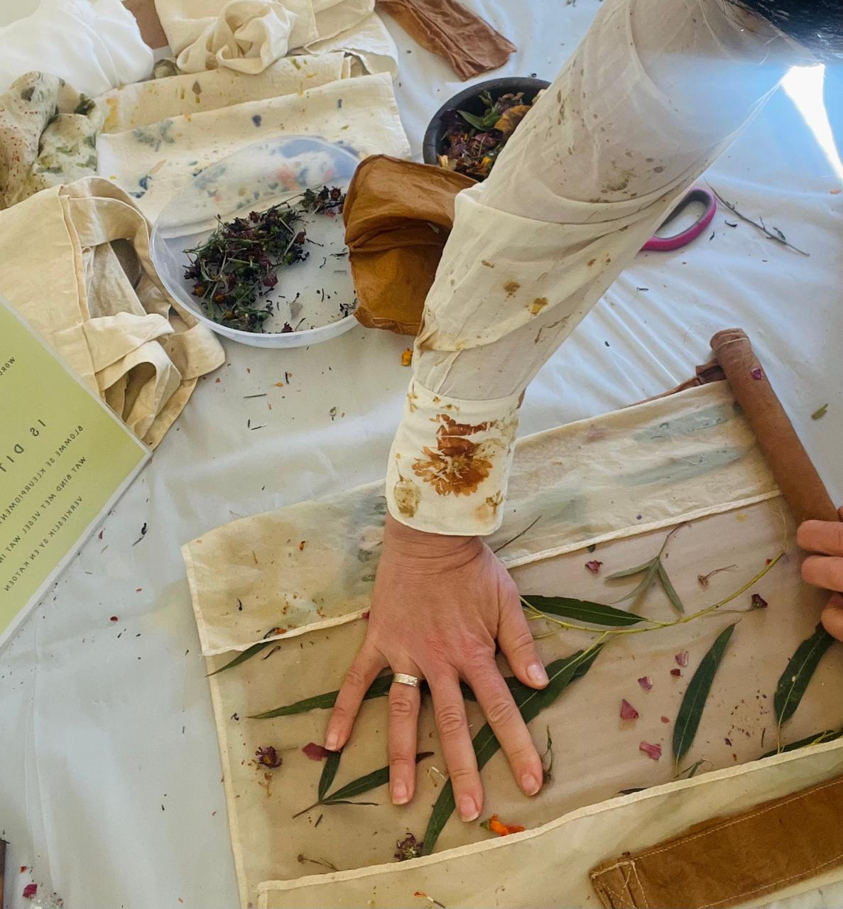 Hands laying eucalyptus leaves onto cloth during a workshop